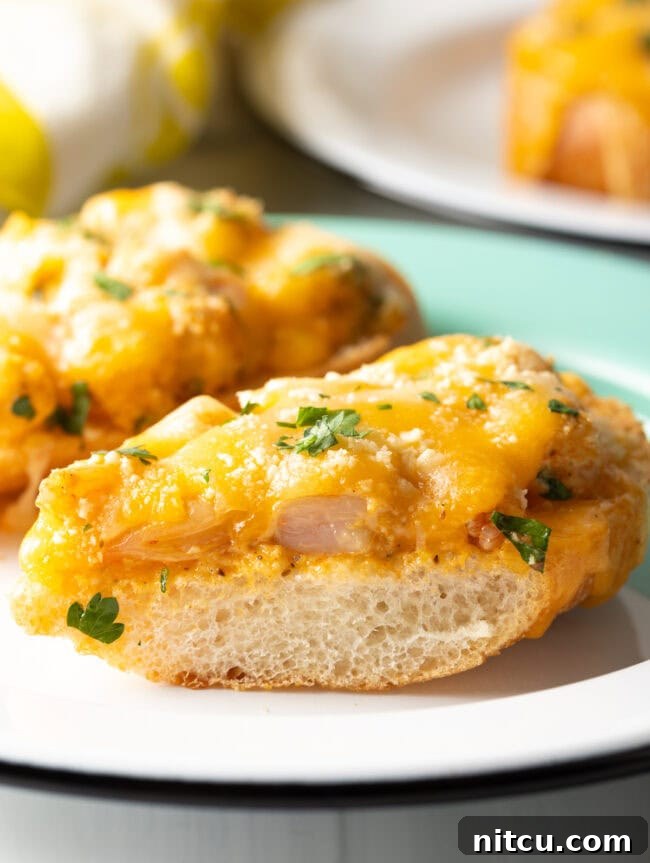 Cajun Shrimp Crostini 13 A close-up view of a baked shrimp toast with perfectly melted cheese and golden-brown bread, garnished with fresh herbs.