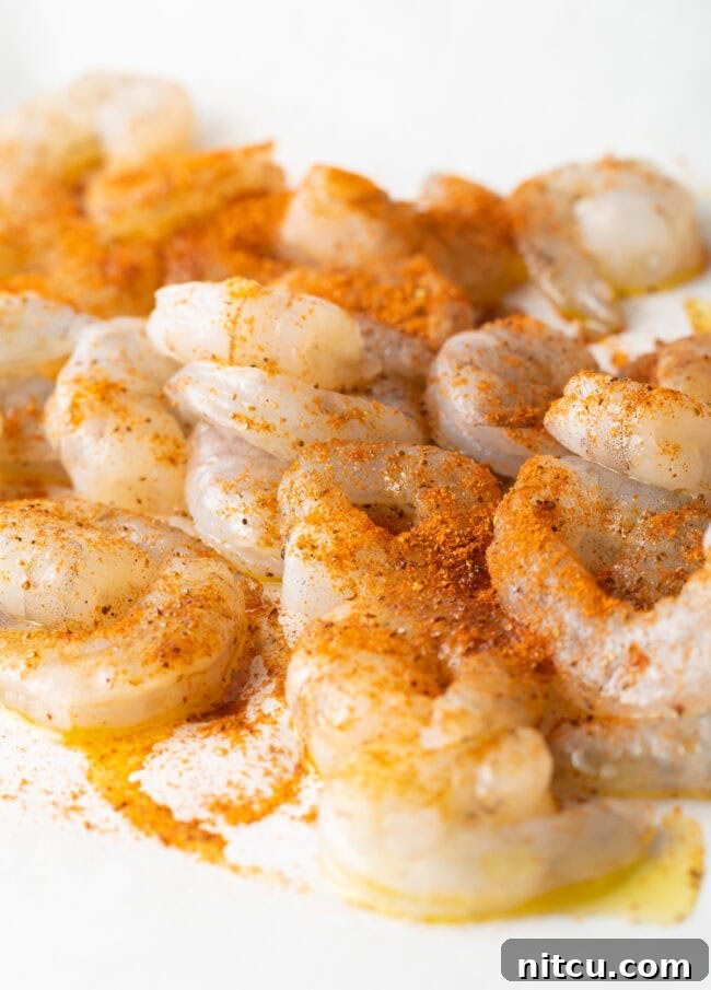 Cajun Shrimp Crostini 4 Raw shrimp uniformly tossed with vibrant Cajun seasonings in a mixing bowl, ready for roasting.