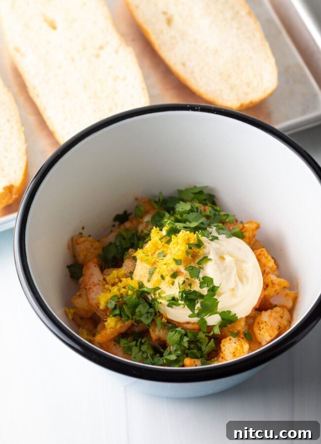 Cajun Shrimp Crostini 6 A mixing bowl containing cooked, chopped shrimp, creamy mayonnaise, vibrant lemon zest, and fresh parsley, ready to be combined.