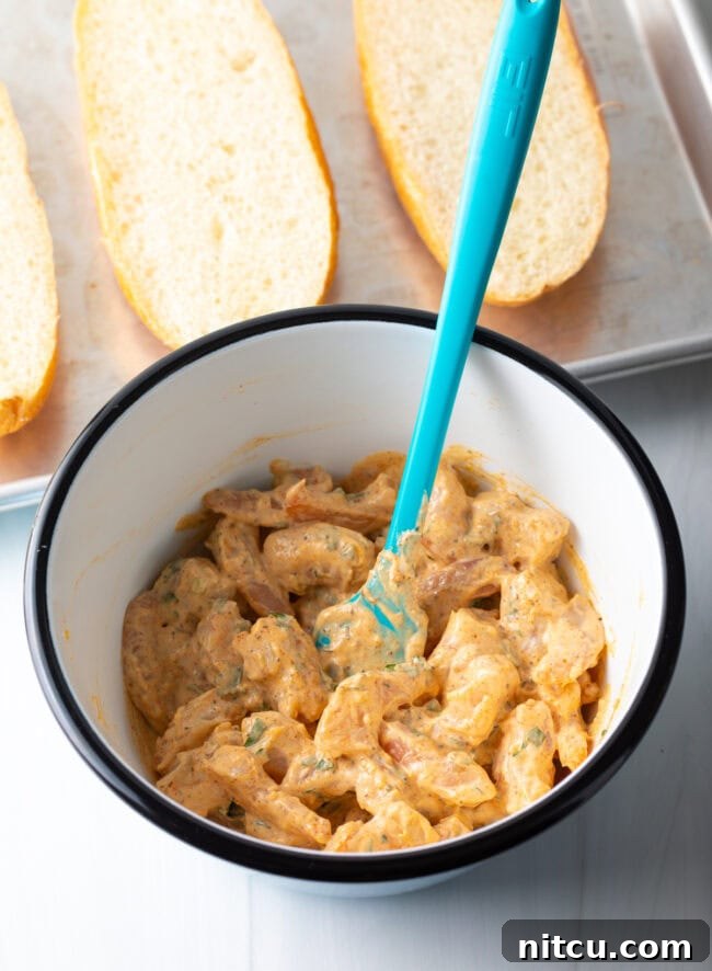 Cajun Shrimp Crostini 7 All shrimp bread filling ingredients perfectly combined in a bowl with a blue spatula, showing the creamy, textured mixture.