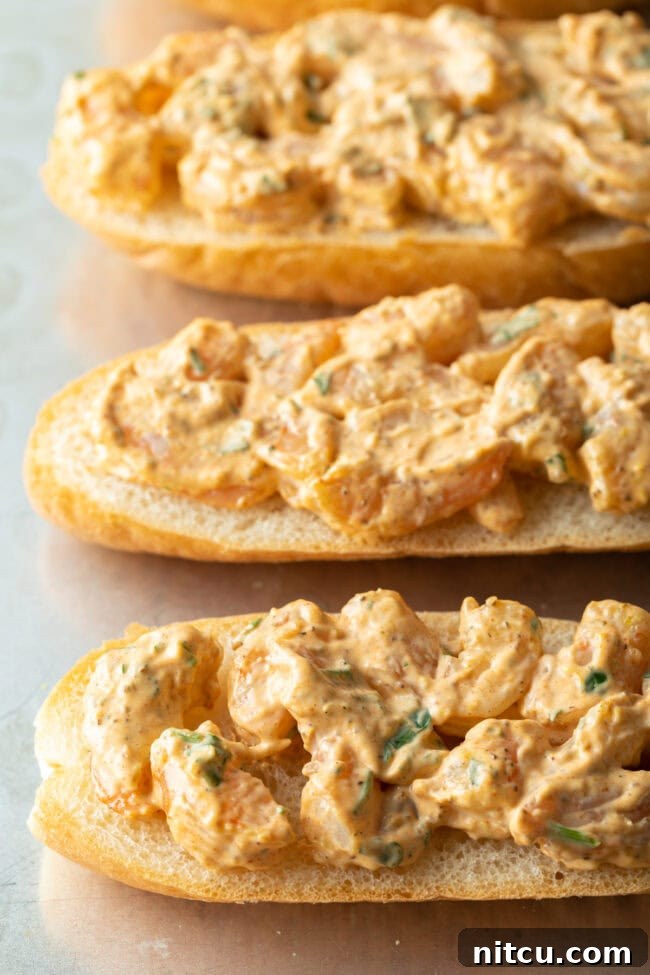Cajun Shrimp Crostini 8 Four pieces of baguette with the savory shrimp and mayonnaise mixture spread evenly across their surfaces, ready for cheese.