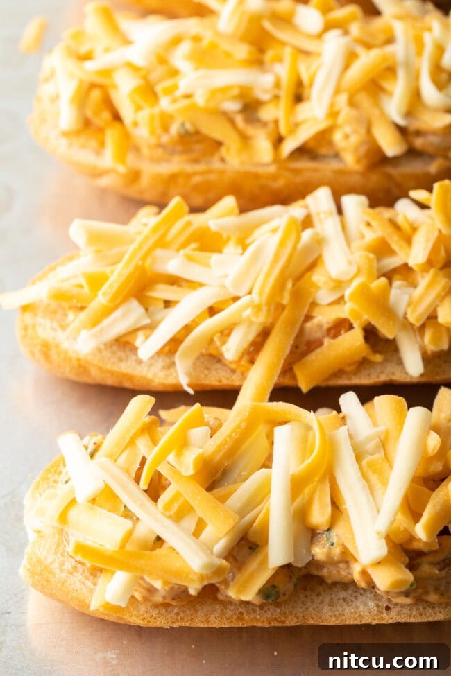 Cajun Shrimp Crostini 9 Shredded cheese generously sprinkled over the baguette pieces topped with the shrimp mixture, preparing for the final bake.