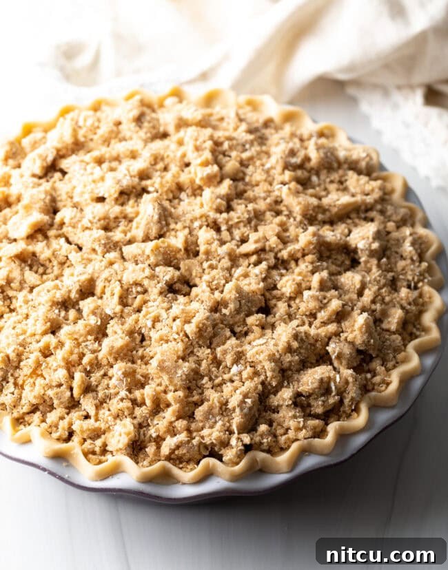 Anytime Peach Pie 12 Sprinkling the oat crumble evenly over the peach filling in the pie crust.