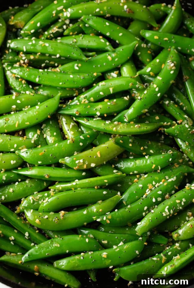 Crispy Garlic Snap Pea Stir Fry 3 Close-up shot of sesame garlic stir-fried snap peas in a large skillet, highlighting the fresh texture and seasoning.