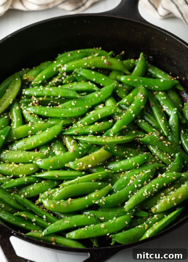 Crispy Garlic Snap Pea Stir Fry 7 Final close-up shot of the stir-fried sugar snap peas in a white serving bowl, garnished with extra sesame seeds.