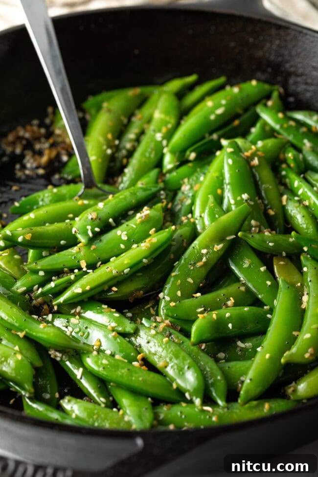 Crispy Garlic Snap Pea Stir Fry 8 Close-up final serving of vibrant green sugar snap peas, perfectly cooked and seasoned, in a rustic bowl.