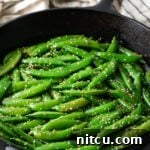 Stir-fried sesame sugar snap peas in a small bowl, garnished with sesame seeds.