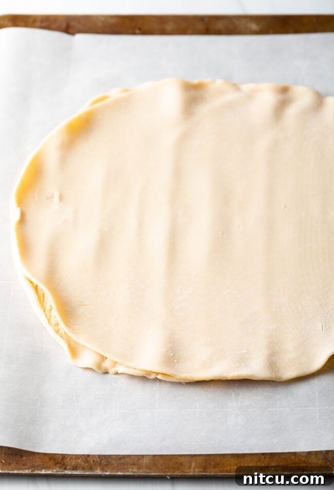 Rustic Italian Tomato Pie 6 Step-by-step image of pie crust being rolled out on a parchment-lined baking sheet.
