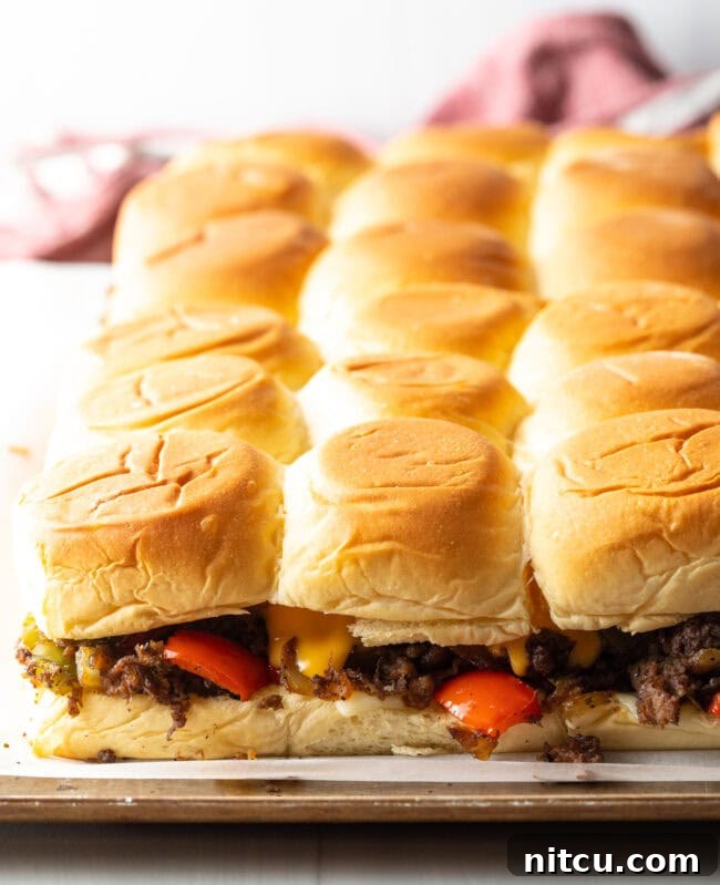 Philly Cheesesteak Bites 12 Baked steak sliders on a pan.