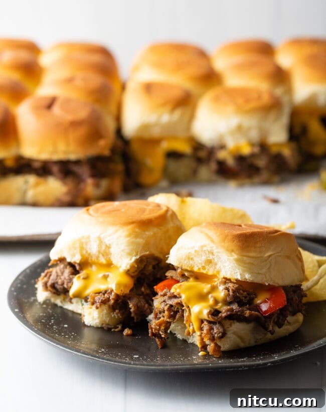 Philly Cheesesteak Bites 13 Sliders in background, two philly cheesesteak sandwiches on a plate.