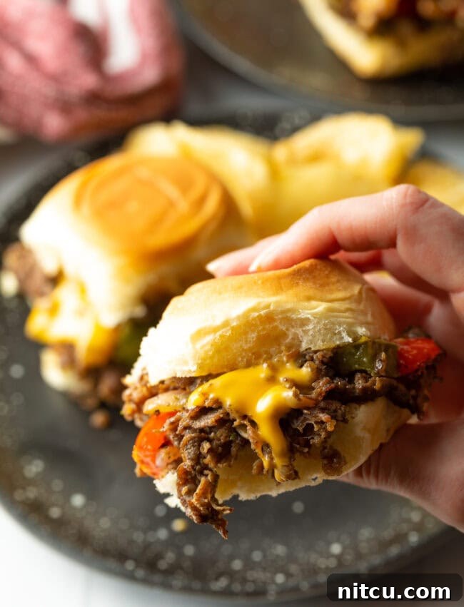 Philly Cheesesteak Bites 15 Hand holding a mini philly cheese steak sandwich to camera.