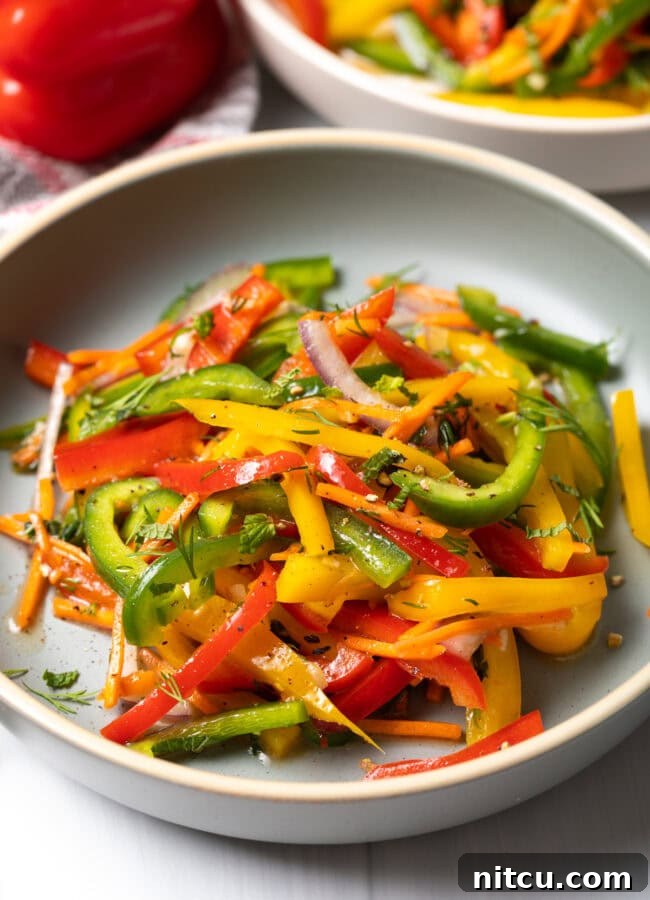 Roasted Pepper Medley 2 A vibrant summer bell pepper salad featuring yellow, green, and red peppers, served in a stylish white plate.