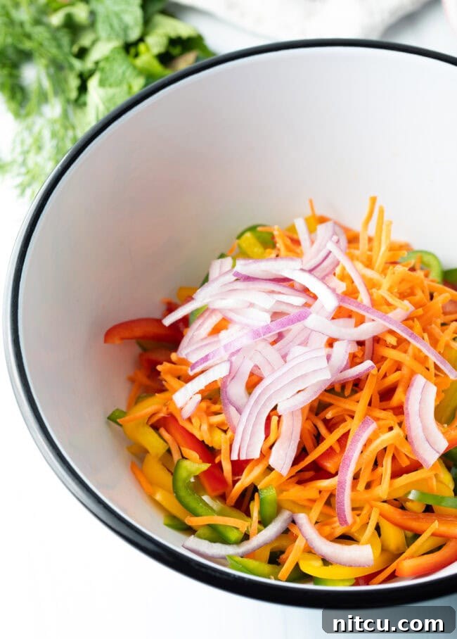 Roasted Pepper Medley 7 Sliced bell peppers, shredded carrots, and thinly sliced red onion in a large mixing bowl, ready for herbs and dressing.