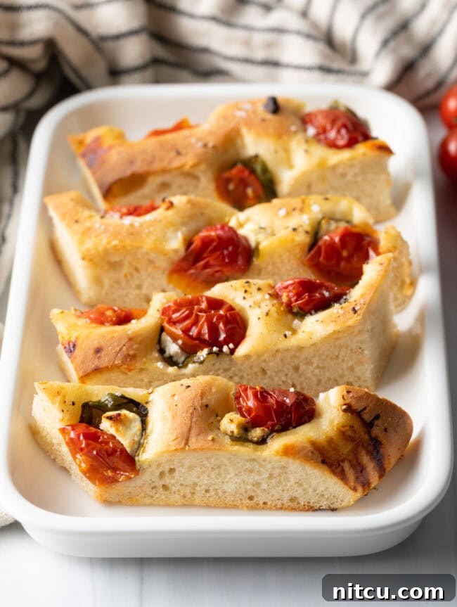 Artisan Tomato Basil Focaccia 2 Slices of tomato basil focaccia bread on a white platter.