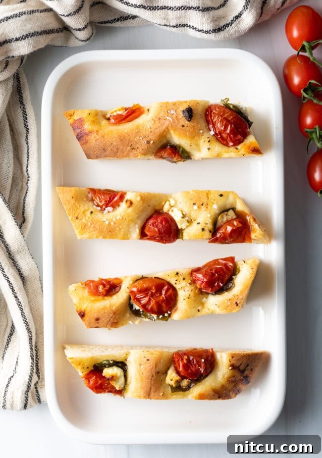 Artisan Tomato Basil Focaccia 12 Top down view 4 pieces of tomato basil focaccia bread on a white platter.
