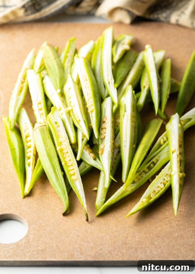 Crispy Air Fryer Okra Fries 13 Raw fresh okra sliced into sections on a cutting board.