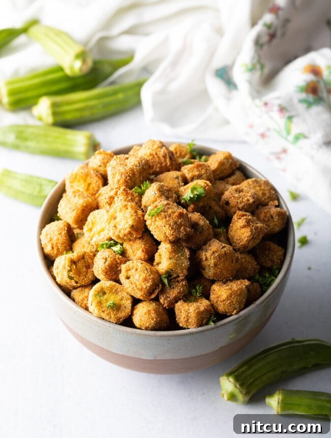 Southern Fried Okra Bliss 3 Top down view of a ceramic bowl filled with freshly fried okra pieces, highlighting their golden brown coating and inviting texture.