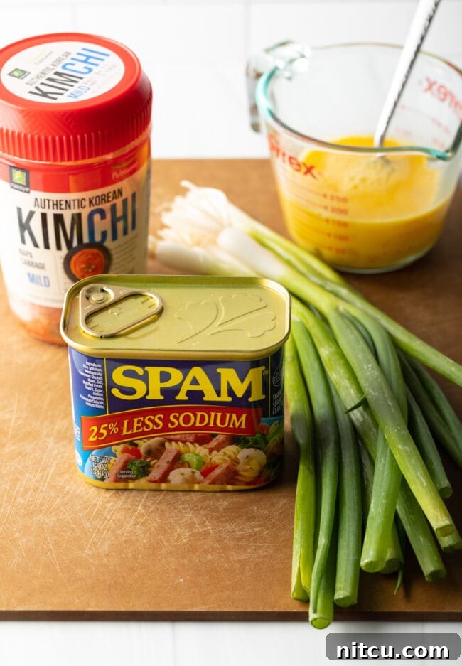 Tropical Kimchi Fried Rice 4 Ingredients on a cutting board: kimchi, can of spam, scrambled raw eggs, fresh green scallions.