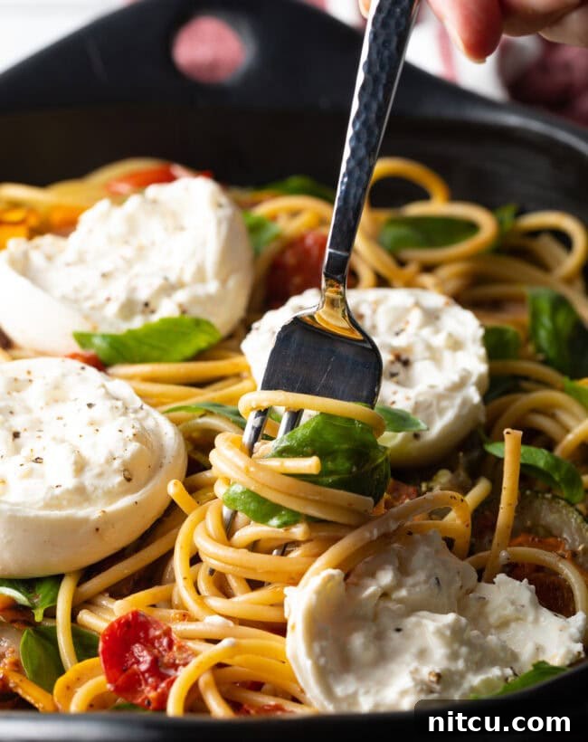 Creamy Burrata and Roasted Summer Harvest Pasta 16 Close-up view of a fork twisting pasta with burrata and roasted vegetables.