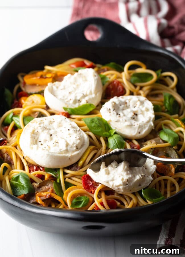 Creamy Burrata and Roasted Summer Harvest Pasta 4 Spoon scooping creamy burrata cheese on top of spaghetti and vegetables.