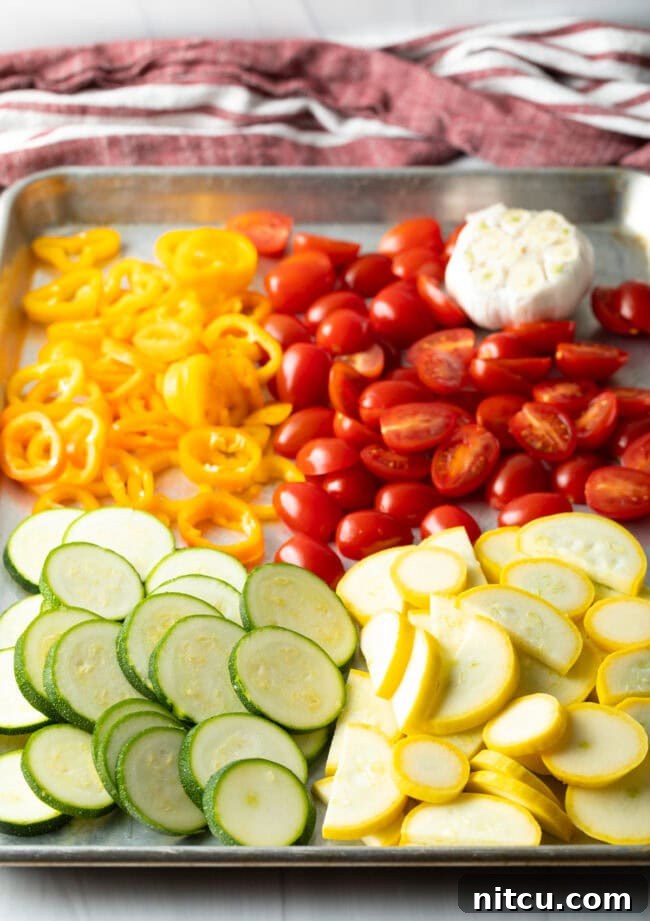 Creamy Burrata and Roasted Summer Harvest Pasta 5 Sheet pan with piles of sliced zucchini, summer squash, tomatoes, peppers, and garlic, ready for roasting.