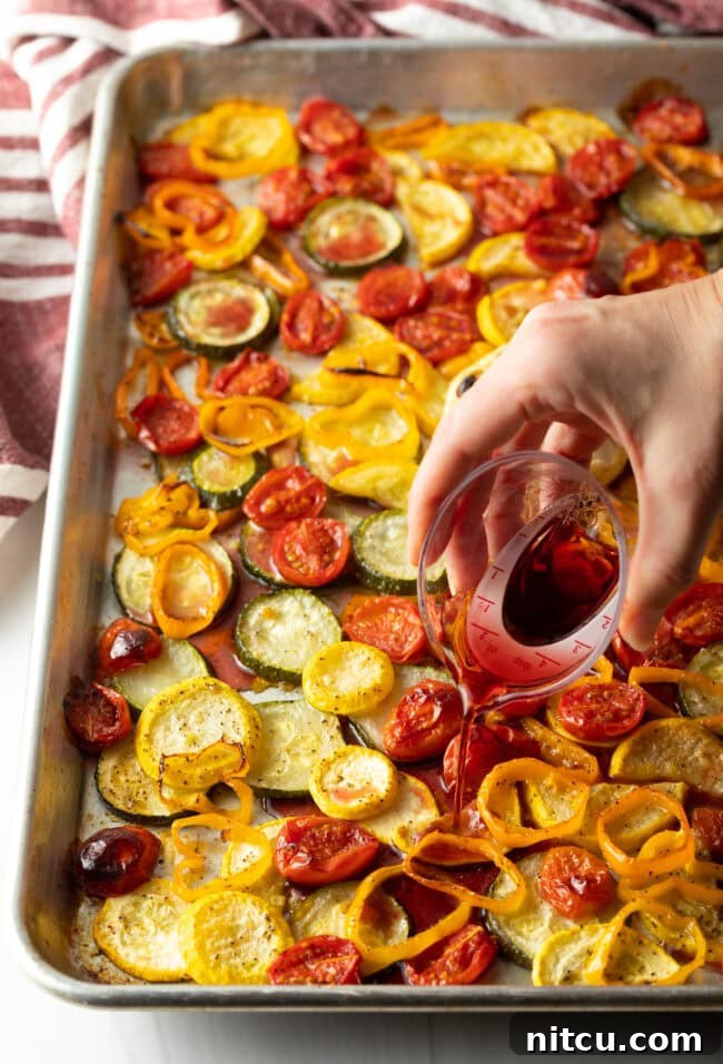 Creamy Burrata and Roasted Summer Harvest Pasta 7 Hand pouring red wine over roasted summer vegetables on a sheet pan.