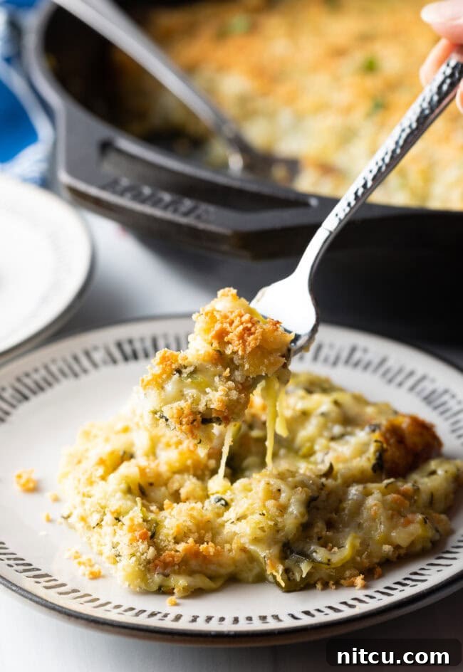 Golden Zucchini Gratin 11 Fork holding bite of cheesy zucchini casserole from the plate to camera.