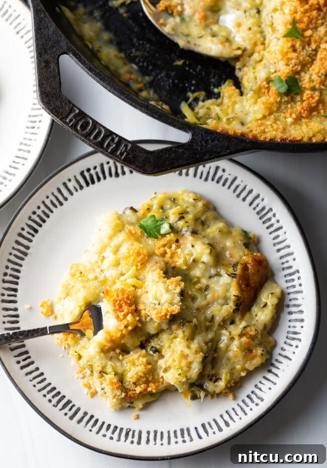 Golden Zucchini Gratin 3 Top down view cheesy zucchini casserole portion on a plate with fork.