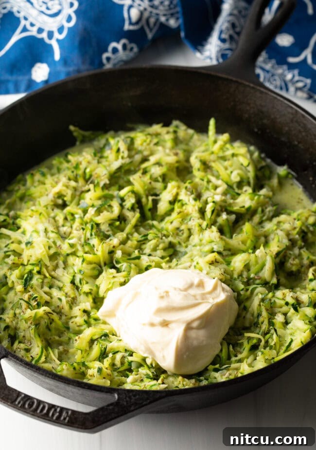 Golden Zucchini Gratin 6 Grated zucchini in a cast iron skillet, large dollop of mayonnaise on top of the zucchini.