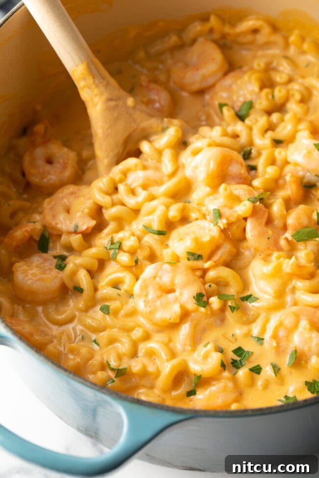 Decadent Shrimp Macaroni and Cheese 11 Closeup view of a pot of creamy macaroni and cheese with shrimp, generously sprinkled with fresh chopped parsley.