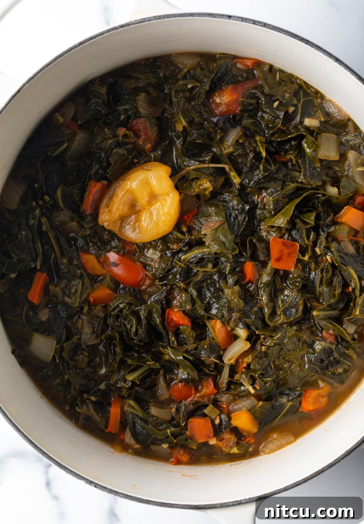 Vibrant Caribbean Callaloo 3 Caribbean stewed greens in large white pot. A large white pot filled with simmering Caribbean stewed greens, showing the rich, vibrant mix of vegetables slowly cooking to perfection.