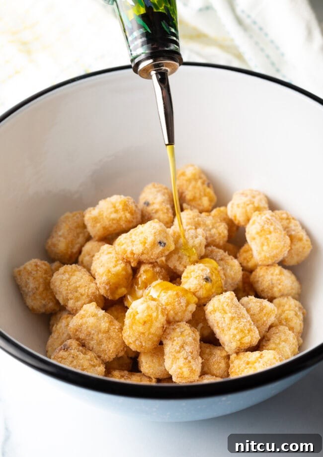 Bowl with frozen tots, drizzling oil on them.