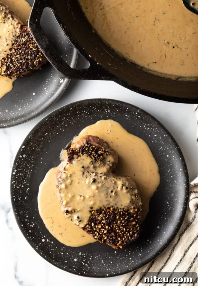 Peppercorn-Crusted Steak with Velvety Cognac Sauce 3 Top down view peppercorn steak with cream sauce on a plate.