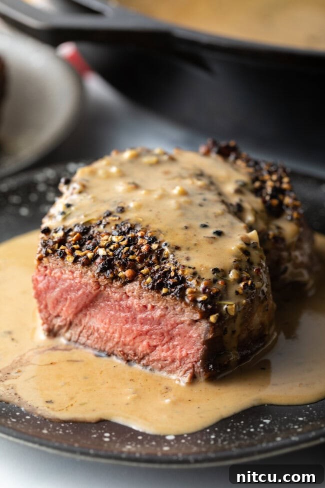 Peppercorn-Crusted Steak with Velvety Cognac Sauce 4 Close view of steak au poivre with bite removed, showing medium rare cook on the inside.