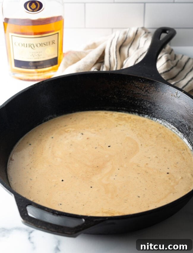 Peppercorn-Crusted Steak with Velvety Cognac Sauce 8 Cream sauce cooking in a cast iron skillet.