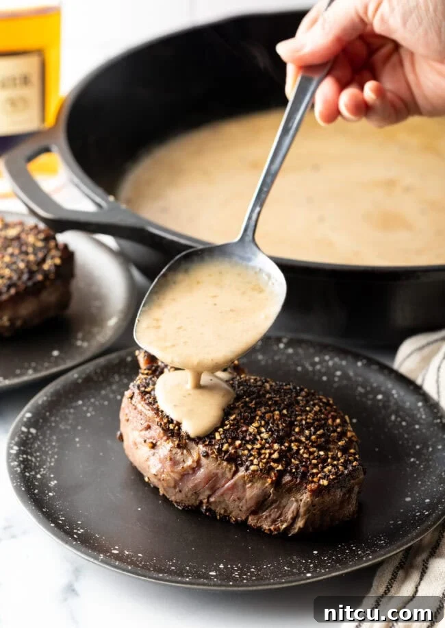 Peppercorn-Crusted Steak with Velvety Cognac Sauce 10 Hand spooning cognac steak sauce over the meat on a plate.