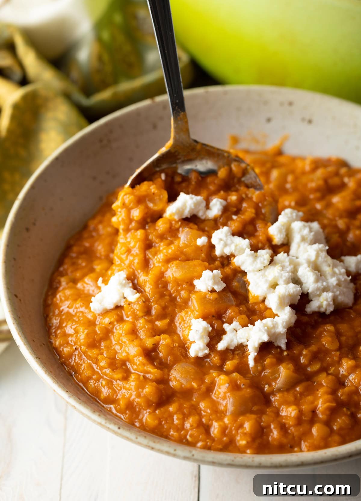 Ethiopian Recipes - Mesir Wat Lentil Stew with Ayib A vibrant bowl of Misir Wot, Ethiopian Red Lentil Stew, garnished with creamy Ayib cheese, ready to be enjoyed.