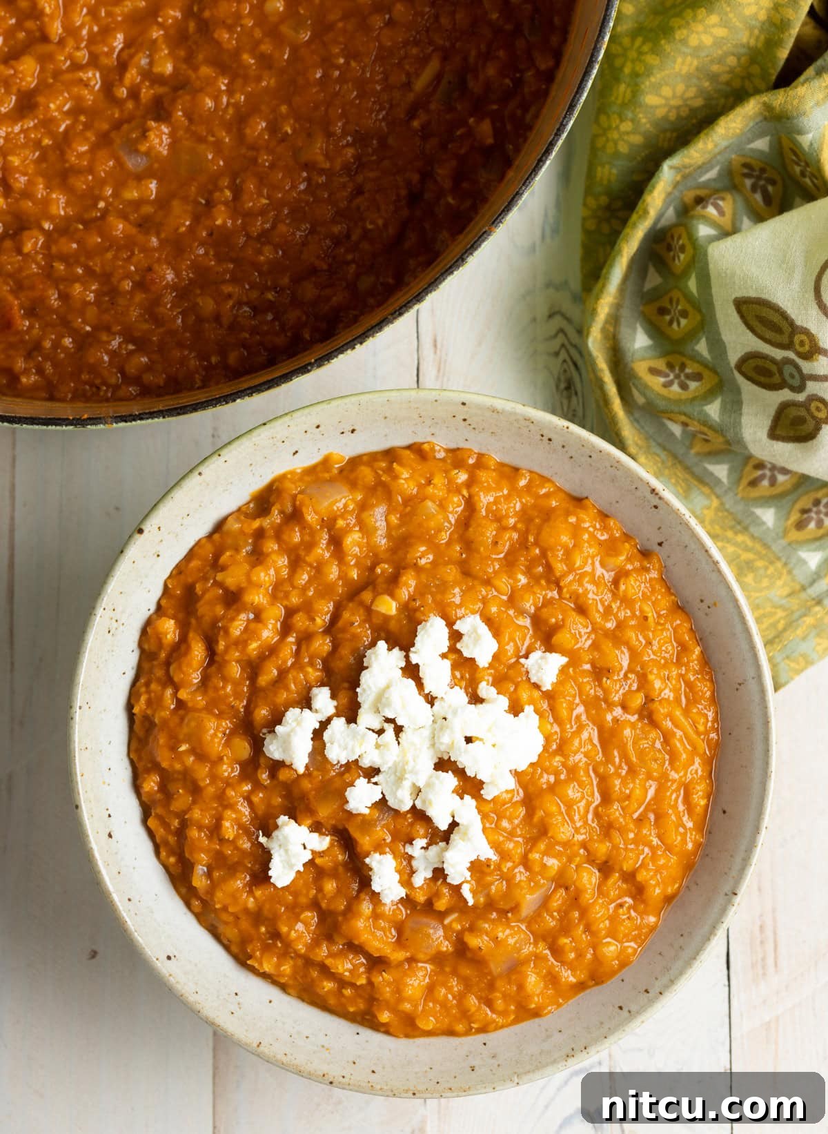 Ethiopian Recipes - Mesir Wat Lentil Stew with Ayib A top-down view of a steaming bowl of Ethiopian Red Lentil Stew (Misir Wot), richly spiced and topped with a creamy dollop of Ayib cheese.
