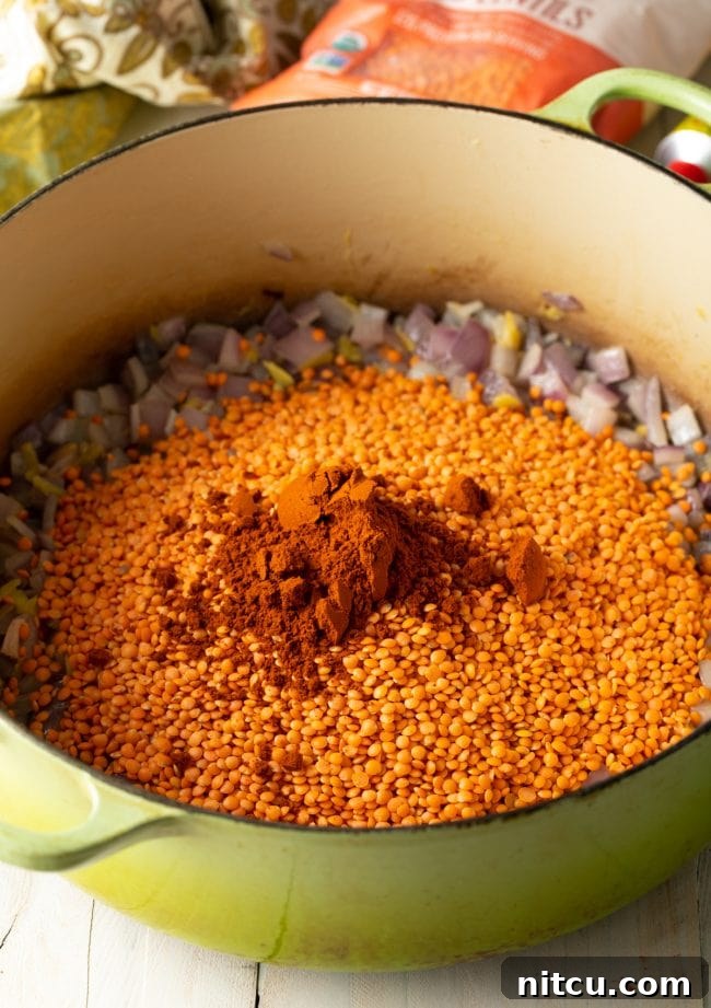 Flavors of Ethiopia 6 A pot filled with sautéed vegetables, covered with uncooked red lentils and a vibrant array of Ethiopian spices, ready for cooking.