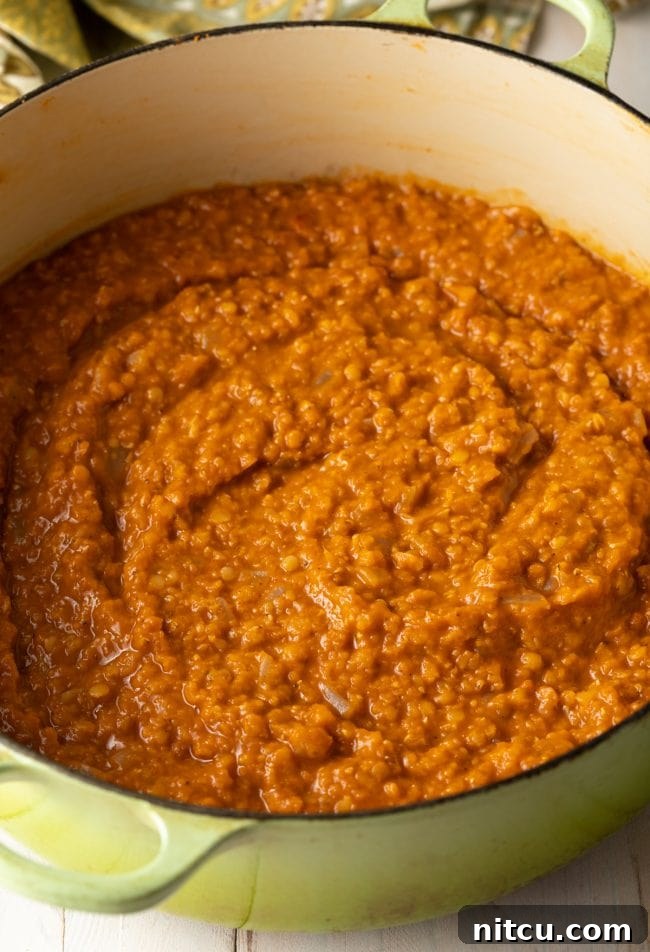 Flavors of Ethiopia 7 The rich, cooked Ethiopian Red Lentil Stew (Misir Wot) simmering gently in the pot, showcasing its thick, porridge-like consistency and deep red color.