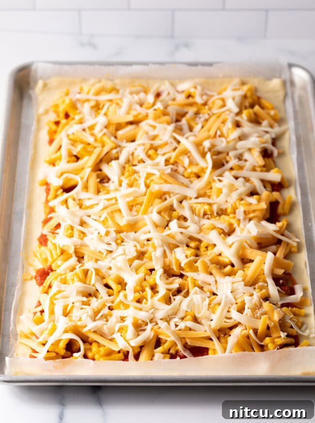 Cheesy Mac Pizza 8 Shredded cheddar and mozzarella cheese sprinkled over mac and cheese layer.