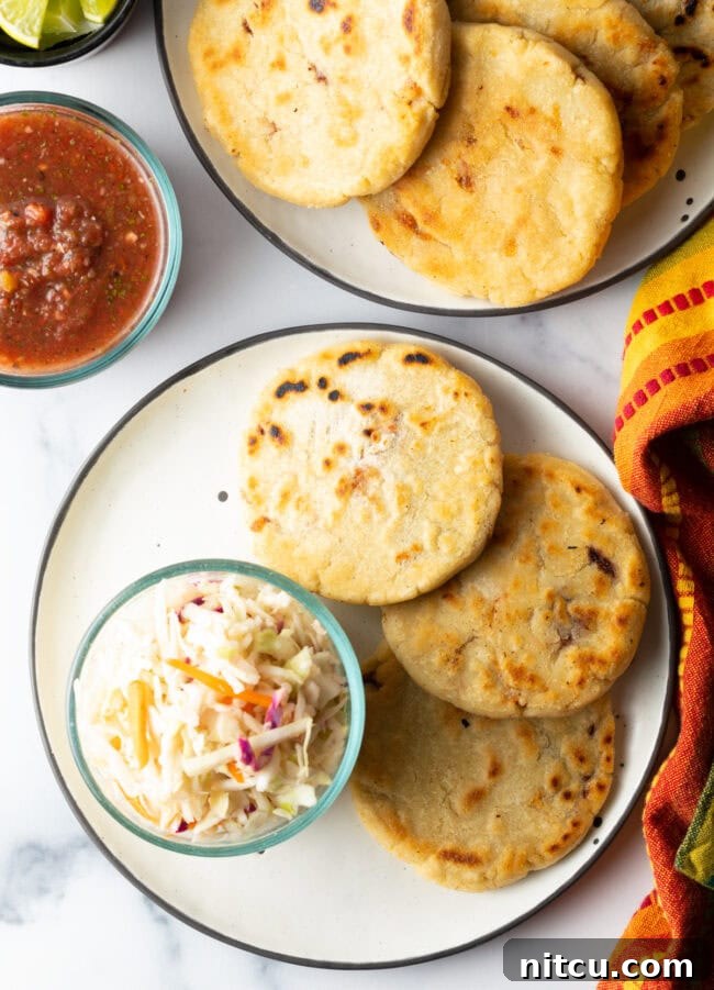 Homemade Pupusas 18 How to Make Pupusas - Top-down view of pupusas on a plate with cold slaw and various toppings.