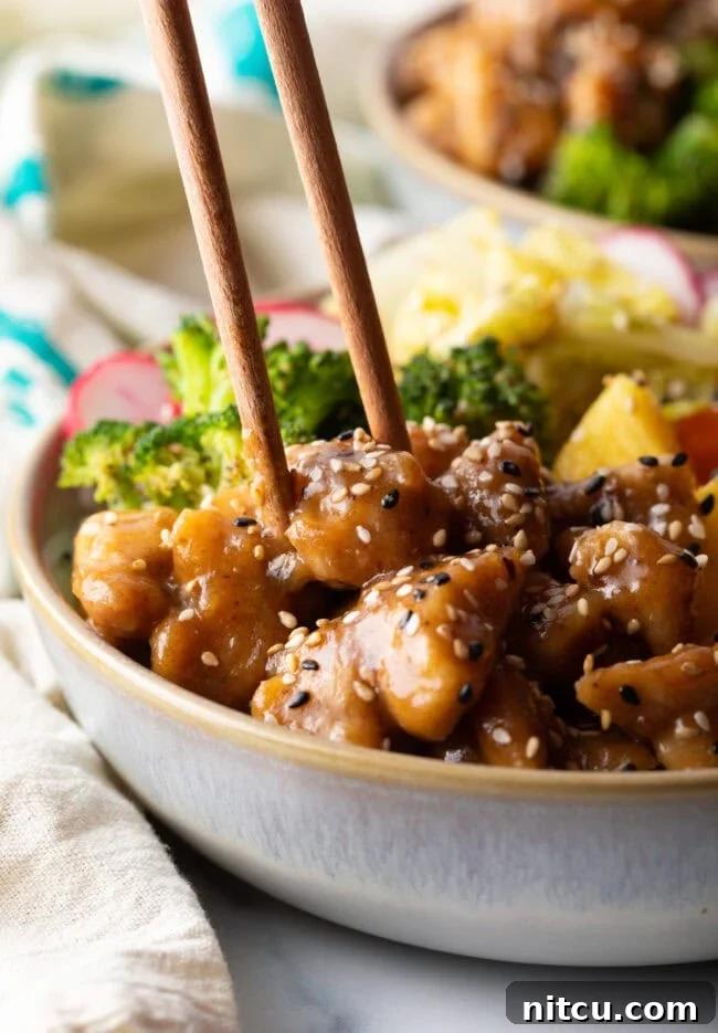 Simply Delicious Chicken Teriyaki Bowl 12 Chopsticks grabbing a piece of chicken from the bowl.
