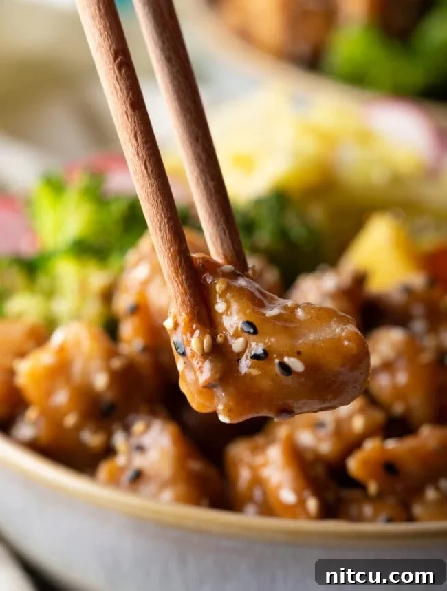 Simply Delicious Chicken Teriyaki Bowl 4 Chopsticks holding bite size piece of chicken to camera.