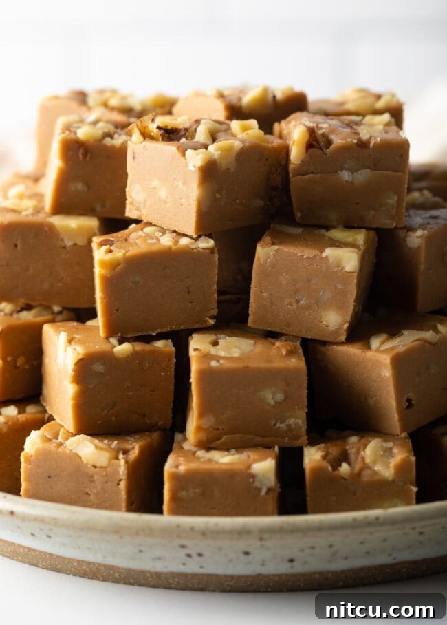 Creamy Maple Walnut Delight 12 Neatly stacked pieces of maple fudge on a plate, showcasing their smooth texture and inviting golden-brown color.