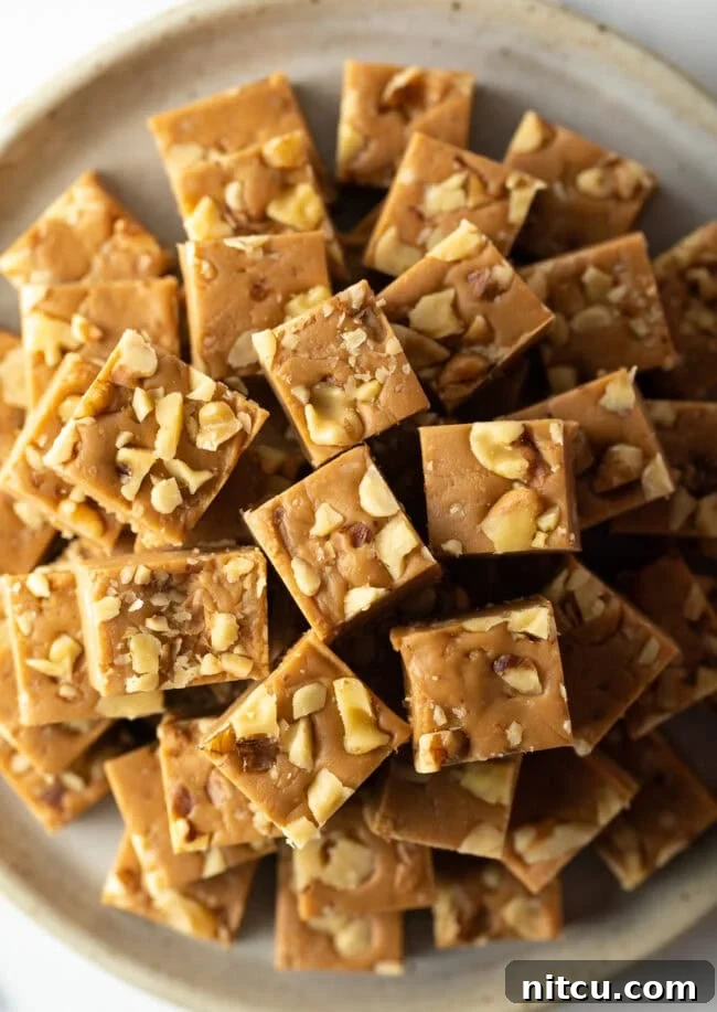 Creamy Maple Walnut Delight 3 Top-down view of beautifully arranged maple fudge squares on a pristine plate, showcasing their perfect shape and inviting golden-brown hue.