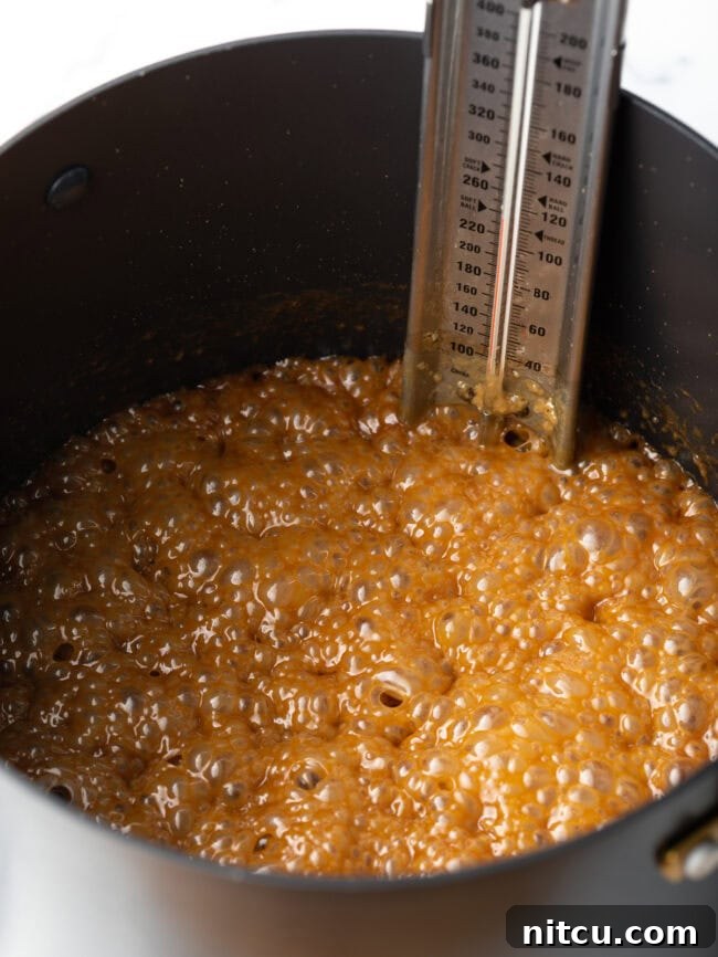 Creamy Maple Walnut Delight 6 Maple syrup and cream mixture bubbling vigorously in a saucepot with a candy thermometer, indicating the soft ball stage.
