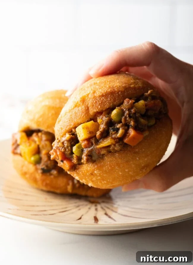 Decadent Cake Creation 4 A hand holding a fat cake generously filled with savory minced meat, showcasing its fluffy interior.