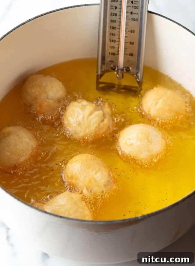 Decadent Cake Creation 8 Dough balls gently frying in hot oil, beginning to turn golden.