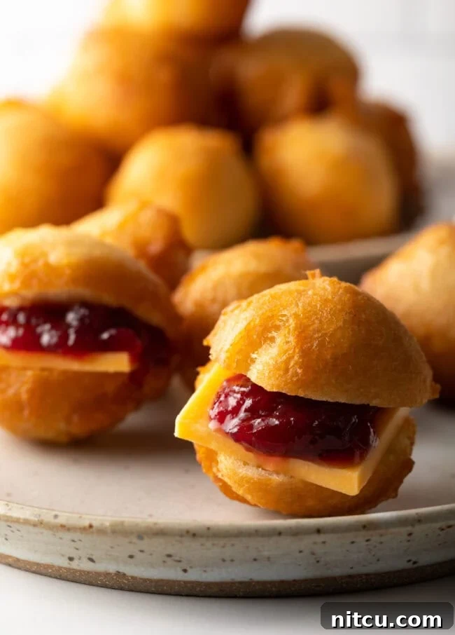 Decadent Cake Creation 10 A close-up view of a Vetkoek cut open, revealing luscious cheese and sweet jam filling.
